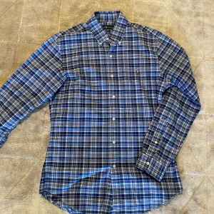  Ralph Lauren skjorta  - Säljer en stilren blå rutig skjorta från Ralph Lauren i storlek M. Den är slim fit och tillverkad i stretchigt material. Perfekt för sommaren, ingen skada. Svarar gärna på frågor