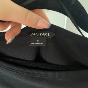 Svart ribbad topp från Monki - Säljer en stilren svart ribbad topp från Monki. Toppen har långa ärmar och en rund halsringning, perfekt för en enkel och snygg look. Passar bra till både jeans och kjol. 🖤