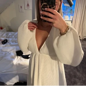 Vit klänning med v-ringning och knytning från NA-KD - Elegant vit klänning med djup v-ringning och långa ärmar. Den har en fin knytning i ryggen som ger en extra detalj. Perfekt för sommaren!! Lånade bilder 