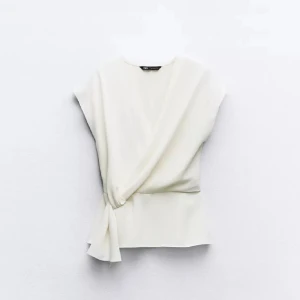 Vit omlottopp från Zara - Superfin vit omlottstopp från Zara köpt förra året men inte kommit till användning på sistone. Finns en sömm som är lite konstigt (bild 3,4) men inget man tänker på! Den syns inte när tröjan är på alls💗Den är inte helt nyskick men skulle säga att den är i väldigt bra skick!!