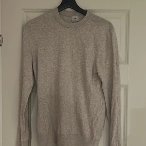 Grå tröja från H&M - Säljer en stilren grå tröja från H&M i slim fit. Tröjan är långärmad och har en rund halsringning med ribbade kanter. Perfekt för en enkel och snygg look. Pris kan diskuteras via meddelande!