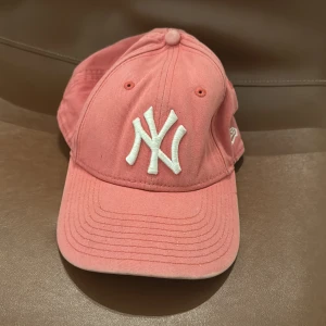 Rosa keps från New Era - Snygg rosa keps från New Era med vit broderad logga framtill. Perfekt för en avslappnad stil. Justerbar passform för optimal komfort.