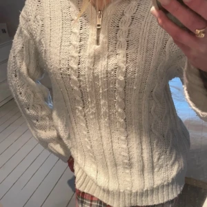 Vit stickad tröja med dragkedja - Mysig vit stickad tröja med kabelstickat mönster och dragkedja framtill. Perfekt för kyliga dagar med sin varma och bekväma design. Tröjan har långa ärmar och en hög krage som kan justeras med dragkedjan. Från h&m