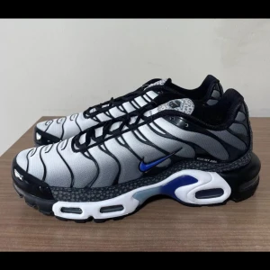 Nike Tn i svart och grått - Snygga Nike Tns sneakers i en stilren kombination av svart och grått med blå detaljer. Perfekt inför sommaren också så hör av dig