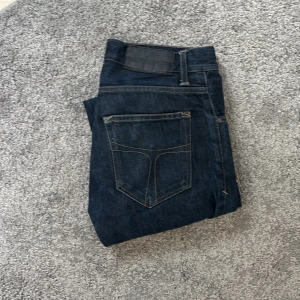 Mörkblå jeans tiger of swe 28/32 - Snygga mörkblå jeans från tiger of Sweden i modellen pistolero . Klassisk femficksdesign med kontrastsömmar och normal passform. Jeansen är tillverkade i slitstarkt bomullstyg och har en stilren look som funkar till det mesta.