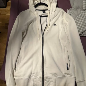 Vit hoodie från Moose Knuckles - Snygg vit hoodie från Moose Knuckles med dragkedja framtill och klassisk logga på bröstet. Äkta vara!!