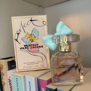 Perfect Marc Jacobs parfym 30ml - Säljer en söt parfym från Marc Jacobs, Perfect, 30ml. Flaskan är genomskinlig med ljusrosa vätska och har ett unikt lock med en stor ljusblå rosett och guldiga detaljer. Kommer med originalkartong med färgglad design. Använd nån gång 