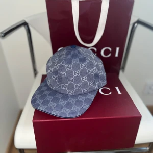 Blå keps från Gucci Canva baseball cap - Snygg blå keps från Gucci med klassiskt GG-monogram över hela kepsen. Kepsen har böjd skärm och är tillverkad i ett super najs material med vit insida. Perfekt accessoar för att lyfta din outfit och visa din stil.