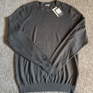 Mörkgrå stickad tröja från Dressmann - Snygg mörkgrå finstickad tröja från Dressmann i mjuk Supima-bomull. Aldrig använd och prislappen sitter fortfarande kvar. Nypris 499kr. Skriv vid frågor!😃
