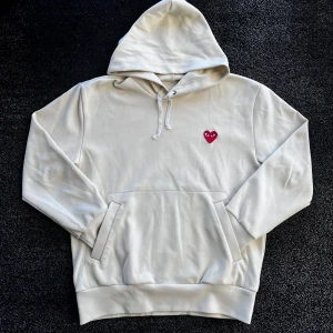 Comme des Garçons CDG Hoodie - Säljer en clean vit hoodie från Comme des Garçons Play med det ikoniska röda hjärtat broderat på bröstet. Skick 9/10, storlek L men passar L/M. Självklart äkta. Pris går att diskutera✅