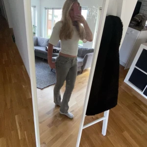 Grå bootcut jeans med låg midja - Säljer ett par gråa jeans med låg midja och bootcut-snitt. Jeansen har klassisk femficksdesign, bälteshällor och dragkedjegylf. Materialet är jeans och färgen är en snygg, lite tvättad grå ton. Perfekta för en chill och trendig look. Storlek 158