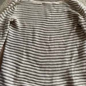 Randig stickad tröja från Esprit - Supermysig stickad tröja från Esprit i vitt och grått med horisontella ränder. Tröjan har lång ärm och är gjord i ett mjukt material som känns skönt mot huden. Perfekt för lager-på-lager och chill dagar.