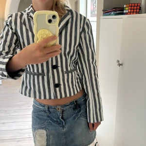 Randig kavaj från Cheap Monday S - Säljer en svartvit randig kavaj från Cheap Monday i storlek S. Jackan är croppad med två knappar framtill, klassisk krage och fickdetaljer. Perfekt för dig som vill sticka ut med en edgy och cool look.