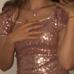 Rosa paljettklänning från Quiz - Superfin rosa kortklänning från Quiz med glittriga paljetter över hela klänningen. Puffärmar och fyrkantig urringning ger en trendig vibe. Klänningen har dragkedja i ryggen och är figurnära. Perfekt för dig som vill sticka ut!