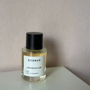 ESSNCE Lemon Eclair Eau de Parfum - Fräsch parfym från ESSNCE med doft av Lemon Eclair. Flaskan är rund i genomskinligt glas med svart lock och vit etikett. Perfekt för dig som gillar citrus och söta toner. Limited edition samarbete med Scents with Naz.