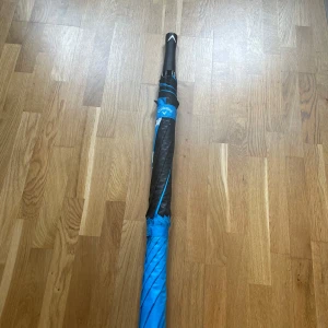 Blå och svart Callaway paraply - Snyggt paraply från Callaway i blått och svart med vit logga. Paraplyet har ett greppvänligt handtag med struktur och sportig look. Perfekt för regniga dagar när du vill hålla stilen på väg till träningen eller skolan.