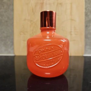 DKNY Red Delicious parfym orange flaska - Parfym från DKNY i modellen Red Delicious. Flaskan är klotrund och har en intensivt orange färg med metallicröd kork. Embossad logga framtill. Flaskan är i glas och känns riktigt trendig och färgstark – perfekt för dig som gillar statement-detaljer.