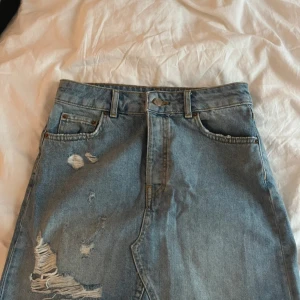 Blå slitne kjol från Gina Tricot - Säljer en kjol från Gina Tricot. Kjolen har snygga slitningar och hög midja.