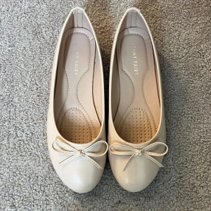 Rosa  ballerinaskor från Jenny Fairy - Snygga rosa  ballerinaskor från Jenny Fairy med rund tå och söt rosettdetalj framtill. Skorna har platt sula och är gjorda i syntetmaterial med en stilren och klassisk look. Perfekta för dig som gillar en enkel och chic stil.