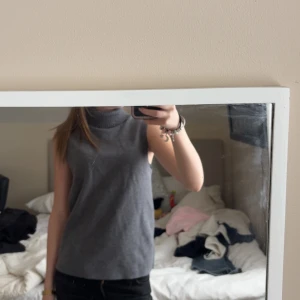 Grå ärmlös polotopp från Zara - Snygg grå polotopp från Zara med hög krage och ärmlös design. Toppen är stickad och har en clean, minimalistisk look som passar perfekt till jeans eller kjol. Perfekt för dig som gillar stilrena och enkla plagg med en modern vibe. Tröjan är helt oanvänd fast utan prislapp då den ramlat av, den är i storlek xs