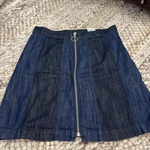 Jeanskjol med dragkedja från H&M - Mörkblå jeanskjol från H&M i kort modell med markerade sömmar och en snygg silverfärgad dragkedja framtill. 