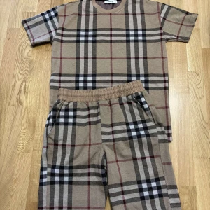Beige rutiga shorts från Burberry - Snygga shorts från Burberry i klassiskt beige rutigt mönster med svarta, vita och röda detaljer. De har elastisk midja för skön passform och är tillverkade i mjuk bomull. Perfekta för dig som vill ha en clean och trendig look med lyxig känsla.