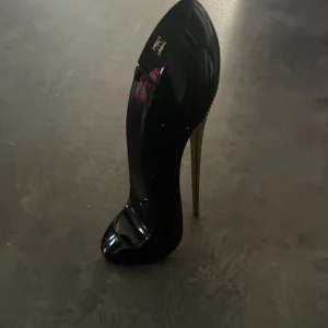 Good Girl parfym från Carolina Herrera - Snygg parfymflaska formad som en svart högklackad sko med gulddetaljer och höga klackar. Flaskan är glansig och riktigt lyxig, perfekt som statement på sminkbordet. Doften är feminin och ikonisk från Carolina Herrera.OBS HALVA KAVR!