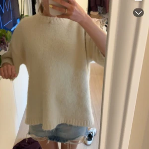 Beige stickad tröja med vida ärmar - Mysig beige stickad tröja med breda, lite kortare ärmar och avslappnad passform. Tröjan har en enkel rund halsringning och ribbade kanter. Perfekt för lager-på-lager och chill vibes.