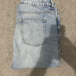 Ljusblå raka jeans - Säljer ett par ljusblå jeans med klassisk femficksdesign och raka ben. Jeansen har normal passform och är tillverkade i denim med en snygg tvättad look. Perfekta för en avslappnad stil.