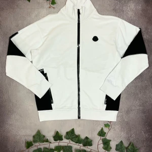 Moncler Zip Up Cardigan (Äkta) - Moncler Zip up Cardigan 🎨 Färg: Vit och Svart 📏 Storlek: M men passar M/L 📐 Mått: Fråga iafall det önskas ♻️ Skick: 10/10  🧵 Material: 100% bomull  ‼️Skickas dagen efter köpet genomförs‼️