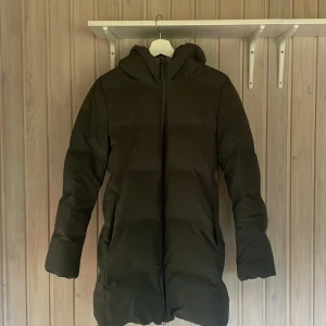 Grön lång pufferjacka från Uniqlo - Säljer en grön lång pufferjacka från Uniqlo💚 med huva och dragkedja. Jackan är vindtät, vattenavvisande och lätt, perfekt för kalla dagar. Enkel och stilren design med två fickor på sidorna och raka ärmar. Inga hål eller fläckar!💓 så sjukt mysig och perfekt till vintern❄️storlek M men för min del mer som en S!😍