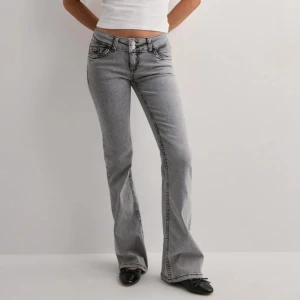 Grå bootcut jeans från Nelly  - Säljer ett par grå lågmidjade bootcut jeans från Nelly med broderi på bakfickorna. Nästan helt oanvända 💗Alla bilderna är mina förutom den första 