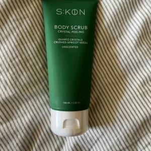 SKON Body Scrub Crystal Peeling - Grön tub med SKON Body Scrub Crystal Peeling, innehåller kvartskristaller och krossade aprikoskärnor. Oparfymerad och rymmer 100 ml. Perfekt för att ge huden en fräsch känsla och silkeslen finish.