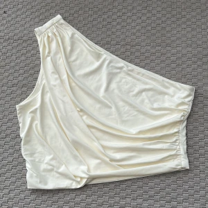 Champagnefärgad oneshoulder topp M - Snygg champagnefärgad topp i satin med oneshoulder-design. Toppens draperade tyg ger en lyxig känsla storlek M