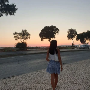 Blommig blå kortkjol från Shein - Supersöt blå kortkjol från Shein med vitt och orange blommönster. Kjolen har volangkant och resår i midjan för en bekväm passform. Perfekt för varma dagar och ger en fräsch och somrig vibe till din outfit.