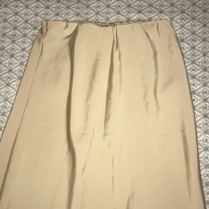 Beige långkjol i enkel stil - Säljer en stilren beige långkjol med rak passform. Kjolen har en minimalistisk look utan synliga detaljer eller mönster, perfekt för dig som gillar en clean och klassisk vibe. Passar till många olika outfits och är superenkel att matcha. Aldrig använd!