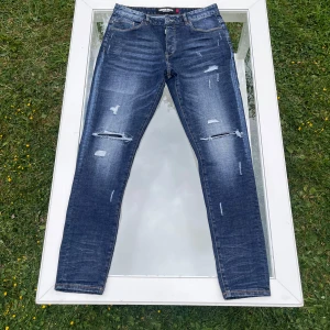 Lorenzo Veratti Iconology+ Distressed Jeans - Säljer ett par Lorenzo Veratti Iconology+ jeans i mörkblå tvätt med kraftig faded look och designade slitningar. Slim fit modell med modern passform. Bra skick utifrån att slitaget är en del av designen. Bara att höra av dig vid minsta fundering!