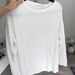 Vit långärmad tröja - Enkel och stilren vit långärmad tröja från Lager157 i mjuk bomull. Tröjan har rund halsringning och en avslappnad passform, perfekt för en clean och minimalistisk look. Passar till allt och är superlätt att styla med andra plagg. Önskar du veta exakta mått? Tveka inte att höra av dig!