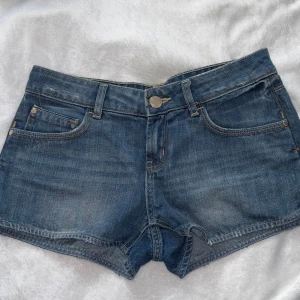 Blå jeansshorts från Gina Tricot - Skitsnygga blåa jeansshorts från Gina Tricot med guld detaljer på knapparna. Snygg, enkel design med normal passform och slitstarka sömmar. Storlek 36.