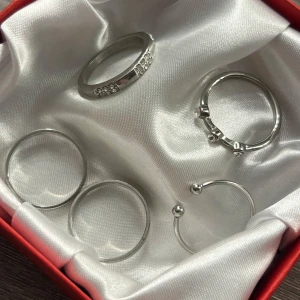 Set med fem silverfärgade ringar - Fem stilrena ringar i silverfärg, varav en med små gnistrande stenar och en med dekorativa kulor. Perfekta att mixa och matcha för en trendig look. 