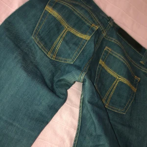 Blå bootcut jeans från Tiger of Sweden - Snygga blå jeans från Tiger of Sweden med bootcut. Färgen är som på första bilden. Köpta secondhand men har ej kommit till användning. (Färgen är ”blågrön”). Kom gärna med prisförslag!