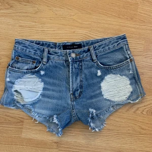 Blå slitna jeansshorts från Line Up - Snygga blå jeansshorts från Line Up med medel/låg  (beroende på vad man tycker) midja och fransiga kanter. Shortsen har stora slitningar framtill och klassiska fem fickor. Perfekta för sommaren. Köpte second hand men har tyvärr blivit för små. Jättebra skick. Ser ut som Levis men det är märket Line Up. Står ingen storlek med skulle säga XS-S😆🥰🥰