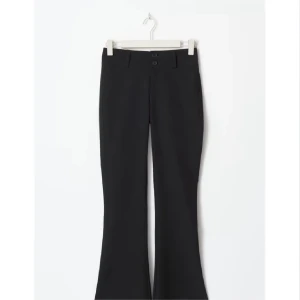 Svarta bootcut kostymbyxor - Snygga svarta kostymbyxor med bootcut-snitt och hög midja. Byxorna har två knappar framtill, bälteshällor och fickor med lock och knapp bak. Perfekta för en clean och stilren look. Använda en gång!☺️