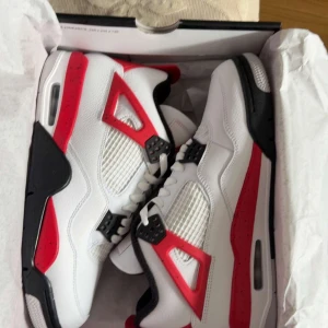 Nike Air Jordan 4 Fire Red sneakers - Nike Air Jordan 4 Fire Red med vit ovandel i skinn, röda och svarta detaljer samt meshpaneler. Klassisk Jumpman-logga på plösen och hälen. Snygg och ikonisk siluett med snörning och platt sula. Perfekta för dig som vill sticka ut med en retro vibe. Hör av dig gärna! PRISET KAN DISKUTERAS!!