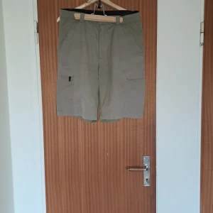 Beiga cargoshorts från Everest - Snygga beiga cargoshorts från Everest med flera praktiska fickor på sidorna och bälteshällor. Perfekta för sommardagar eller äventyr utomhus. Lätta och bekväma med klassisk passform och diskret logga på ena fickan.