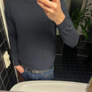 Mörkblå tröja - Säljer en stilren mörkblå tröja med rund halsringning. Tröjan har en diskret textur och långa ärmar, perfekt för en avslappnad look. Passar bra till jeans eller chinos. Märke Liu•Jo