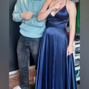 Mörkblå långklänning med snörning -  mörkblå långklänning i satin med djup v-ringning och smala axelband. Använd en gång så i nyskick, klänningen är uppsydd i efterhand och passar någon i längd 160. Fin till skolbalen eller andra högtider 💙ny pris 3000