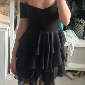 Svart klänning från Oneness - Snygg svart klänning från Oneness med offshoulder-design och volangdetaljer. Perfekt för en kväll ute eller en speciell tillställning.🌸