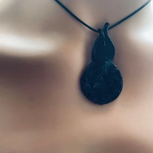 Made by prisförslag- 1 Svart päron  - Formen och färg är det samma, detaljerna olika. Unika handgjorda halsband i lera med svarta och vita hängen i olika former. Varje hänge har en distinkt design, perfekt för att uttrycka din personliga stil. Hängena är fästa på en enkel svart rem. Finns i de andra former och som svart/vit. 