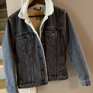 Grå jeansjacka med teddyfoder - Säljer en snygg grå jeansjacka från Lager157 med mjukt teddyfoder. Jackan har knappar framtill och två bröstfickor med lock. Jackan är i mycket fint skick då den endast är sparsamt i två veckor, handtvättad en gång i parfymfritt tvättmedel och inget sköljmedel. 